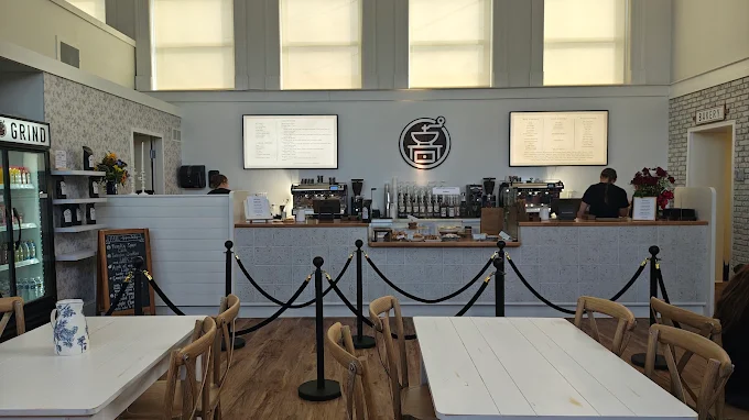 The front counter with two espresso machines, menu screens, and the Rise 'N Grind grinder logo on the wall