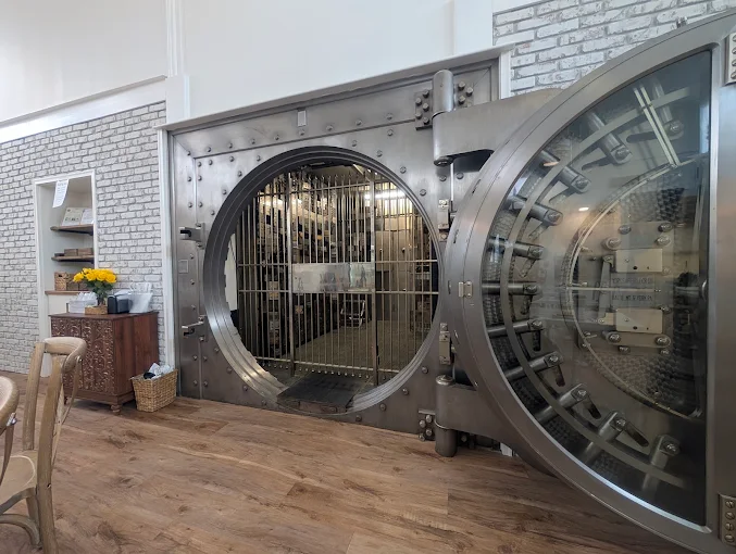 The original round steel bank vault door standing open inside the cafe, with its locking bolts visible